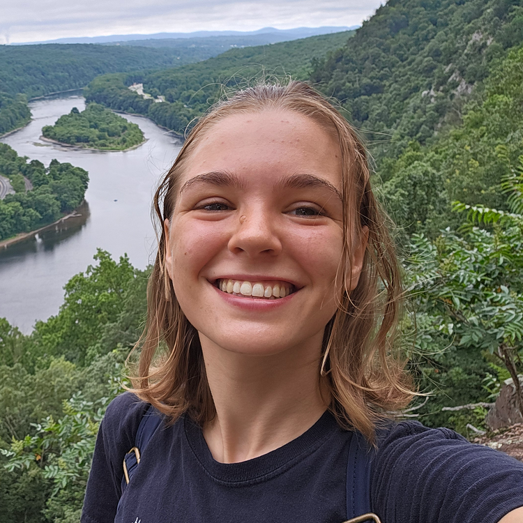 Hailey smiling in front of a view of a river.